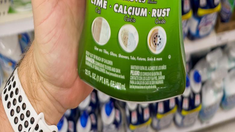 a person's hand holding a spray bottle of Lime-A-Way