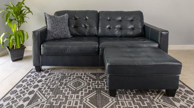 black leather couch with gray and white throw pillow and rug