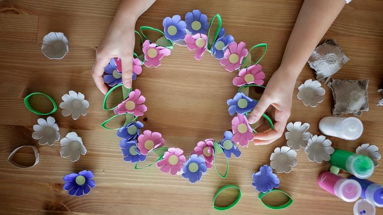 Hands holding a DIY spring-themed wreath made from egg cartons.