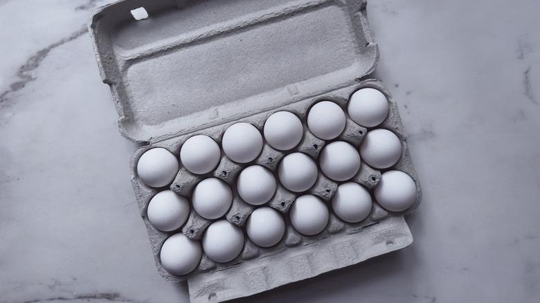 An molded pulp, gray egg carton with 18 eggs.