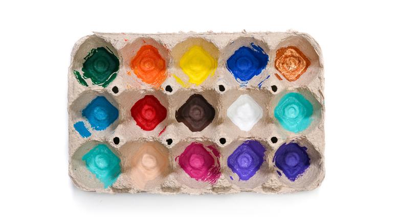 A carton egg tray with paint at the bottom of each mold.
