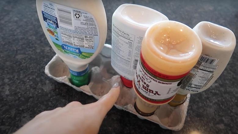 Condiment bottles turned upside down and stored in an egg carton tray.