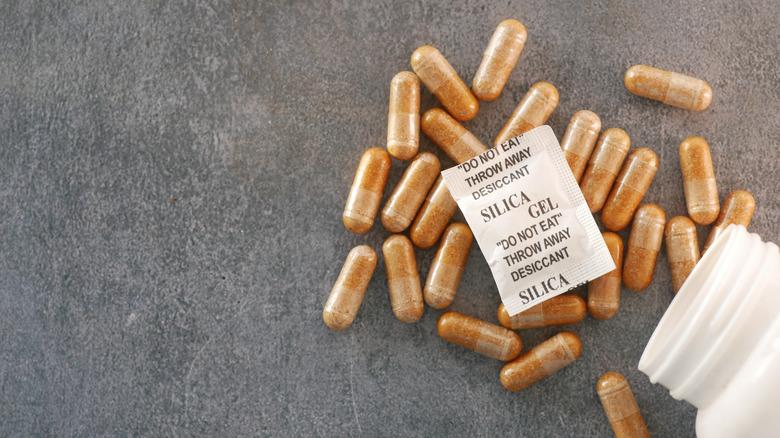 capsule pills spilled out of container with silica gel packet on top