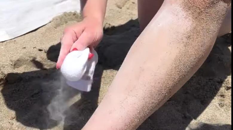 Removing sand from skin with baby powder-filled sock