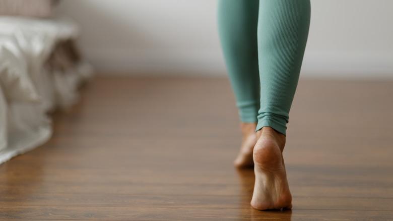 Woman walking on tiptoes on wooden floorboards