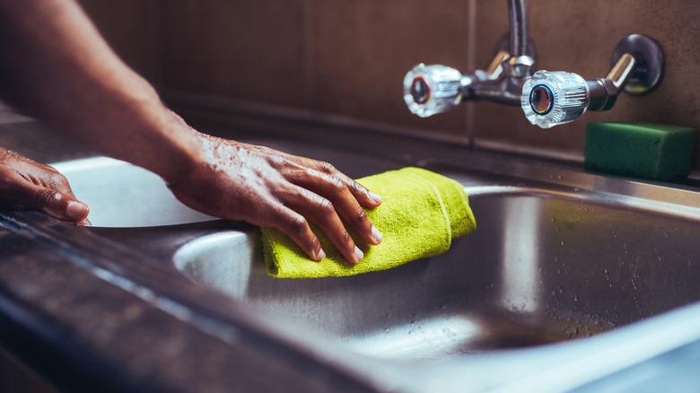 Arm polishing stainless steel sink with a microfiber cloth