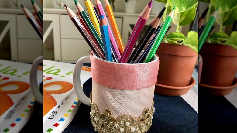 Coffee cup decorated with ribbon and lace, holding colored pencils