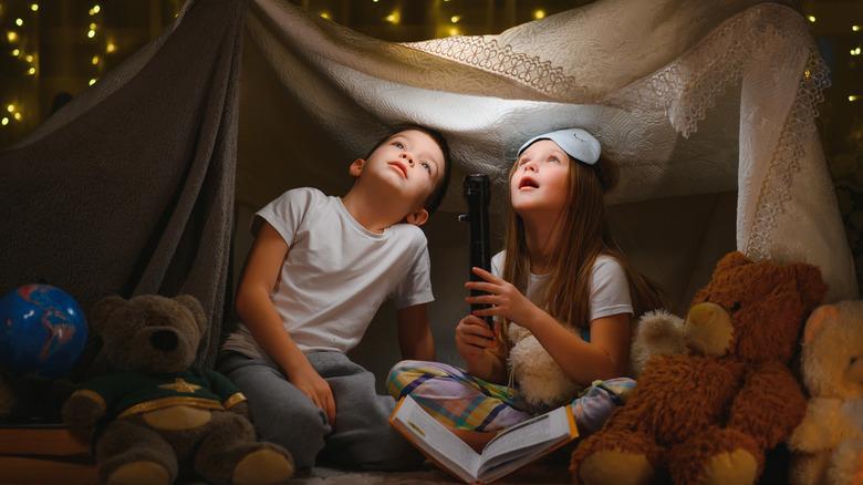 Two children looking up at lights in a sheet fort