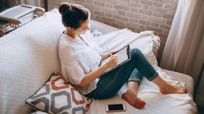 Woman sitting on sofa with tablet
