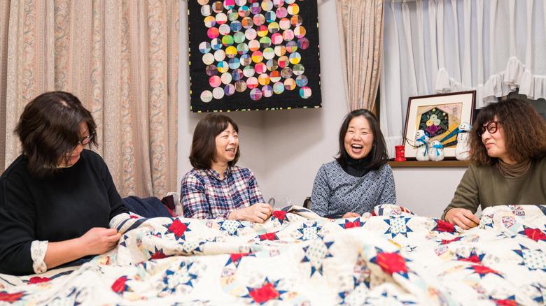four women participating in a quilting bee