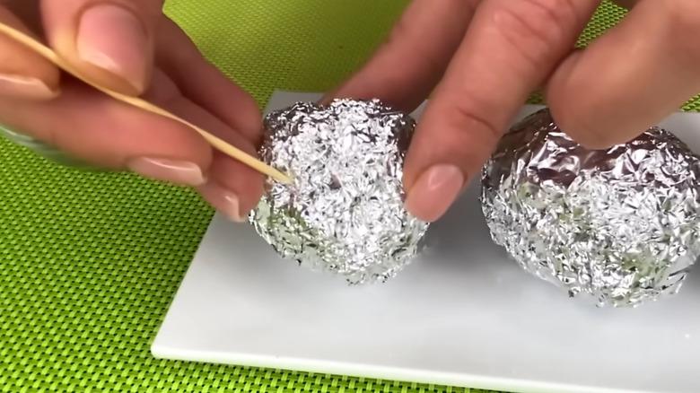 Poking holes in foil ball with a skewer