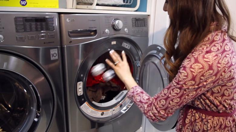 Woman throwing two aluminum foil balls in clothes dryer