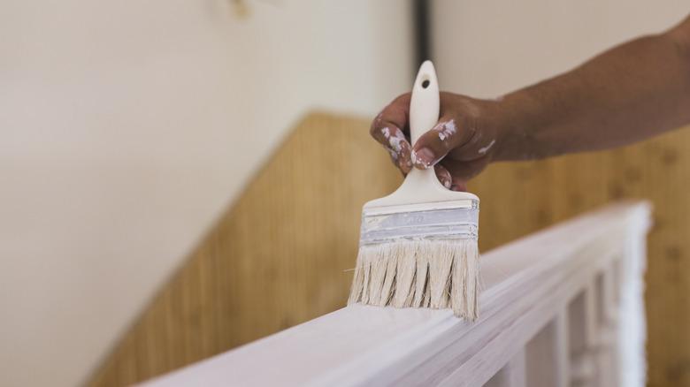 person painting railing with a wet paint brush