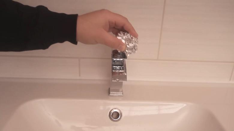 Removing hard water stains with ball of aluminum foil