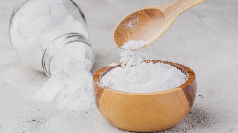 A jar of baking soda spilling over near a bowl of open baking soda.
