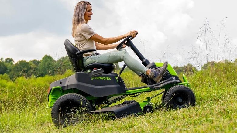 woman driving lawn mower on a grassy hill