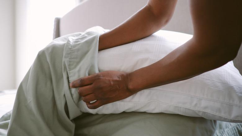 person changing green pillowcase