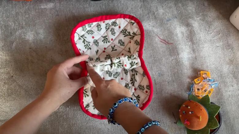 hand pointing to hand-sewn cloth on carpeted surface