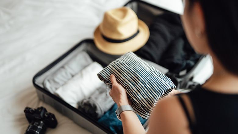 young woman packing suitcase