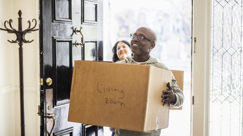 couple carrying cardboard box into home