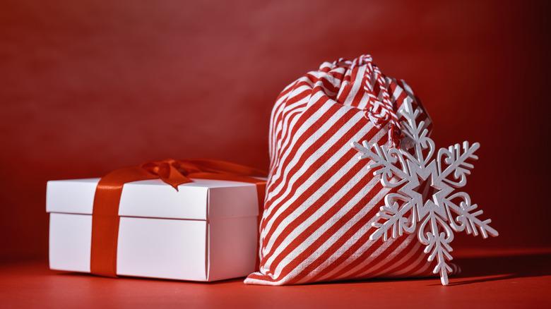 White box with red ribbon and red and white striped sack with snowflake pendant