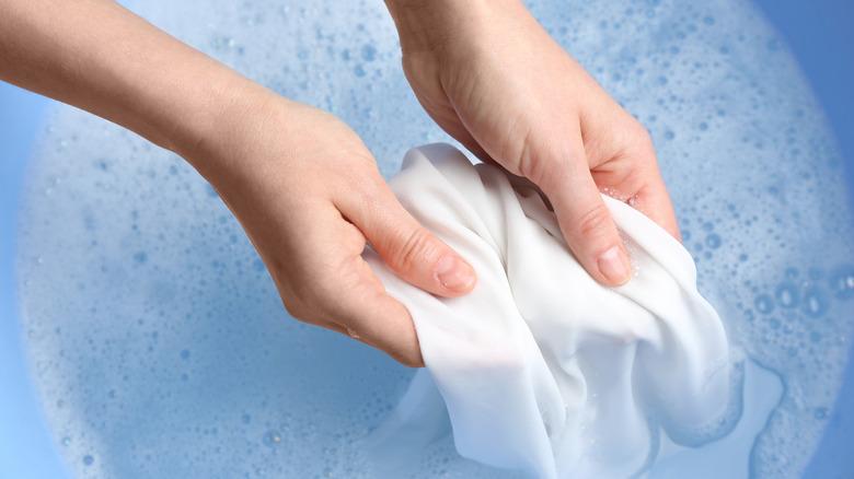 Hands scubbing with shirt from soak