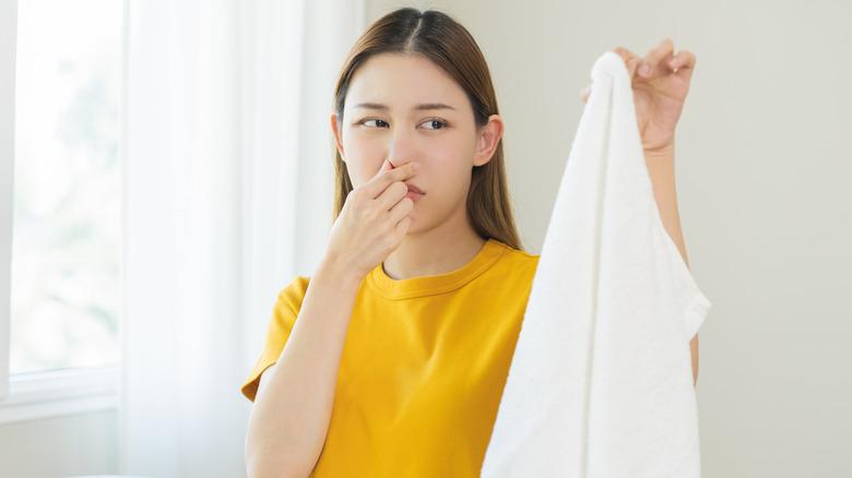 person holding nose while holding up a piece of clothing