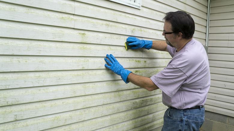 man scrubbing dirty vinyl siding
