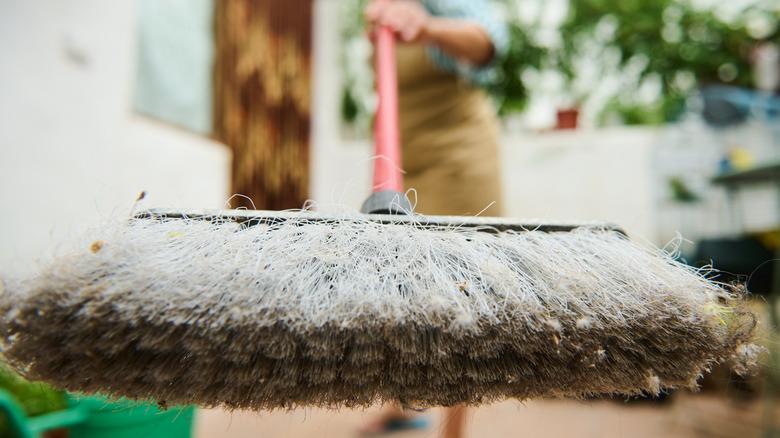 Holding a dirty push broom up