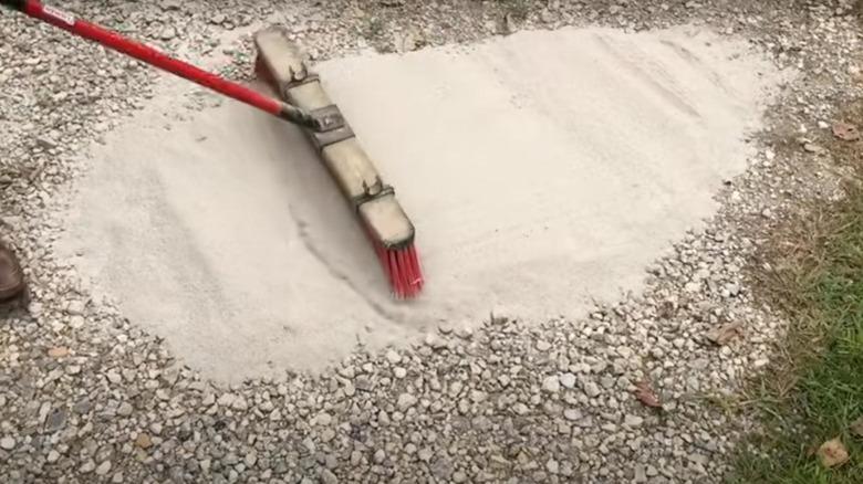 spreading cement powder on a gravel driveway