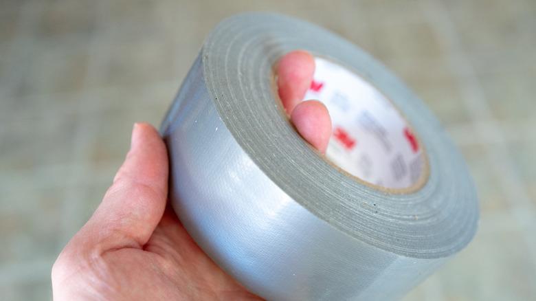 Hand holding roll of duct tape