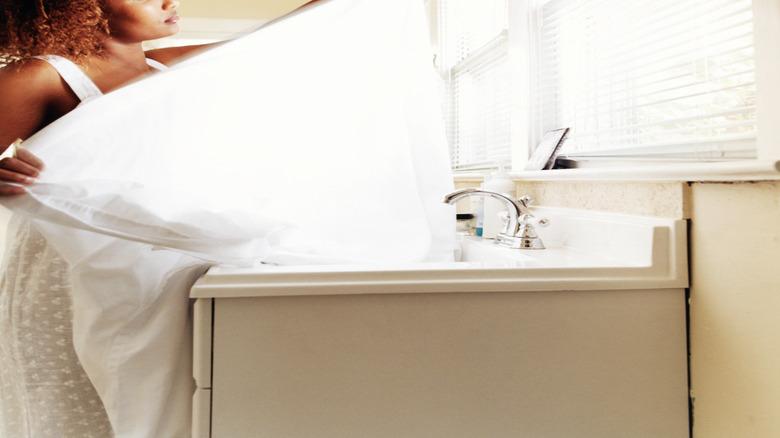 Woman folding sheets in a laundry room