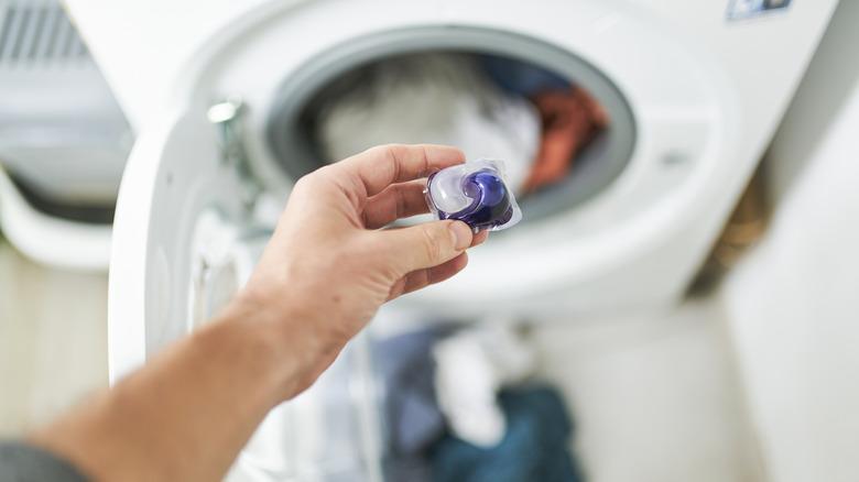 Man tossing pod in laundry