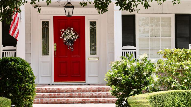 A federalist style home with a red door and black window shutters.
