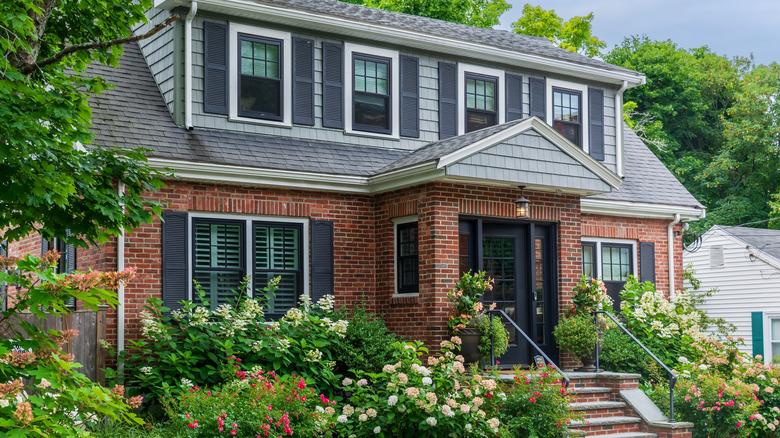 A brick home with a black front door and matching black shutters.