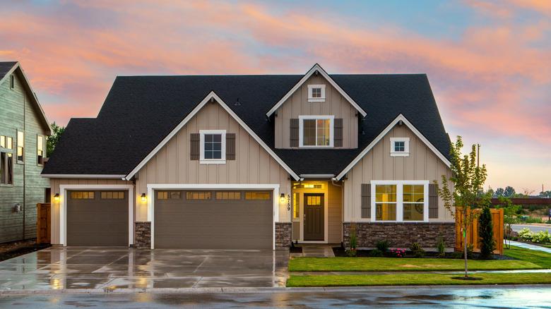 A modern farmhouse with mocha mousse-colored doors, shutters, and garage doors during sunset.