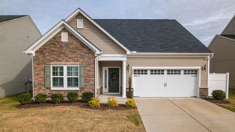 A house with a dark green door and sage green shutters.