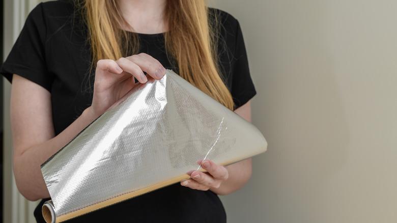 Woman in black T-shirt holding aluminum foil
