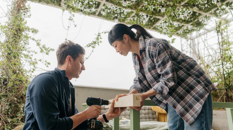 A couple assembling furniture outside on terrace.