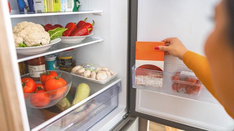 Woman reaching for food in a refrigerator
