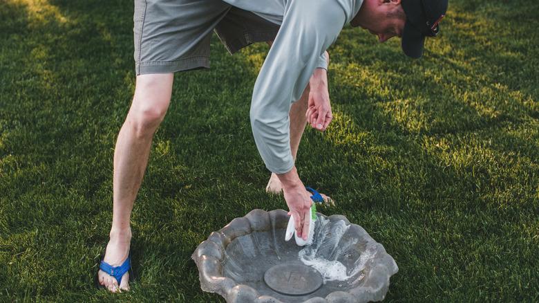 man scrubbing dirty birdbath