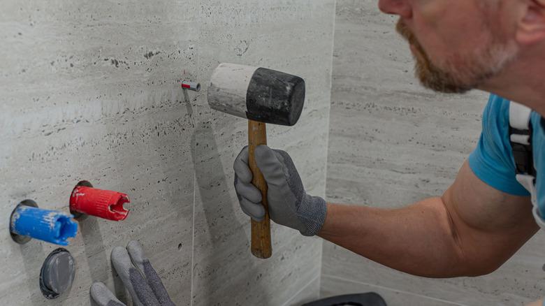 Man hammering anchor into wall