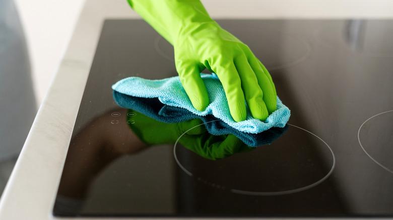 hand wiping down glass stovetop