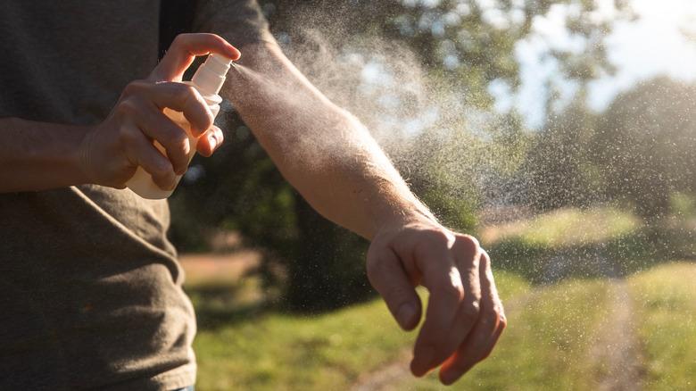 A person is applying insect repellent on their arm.