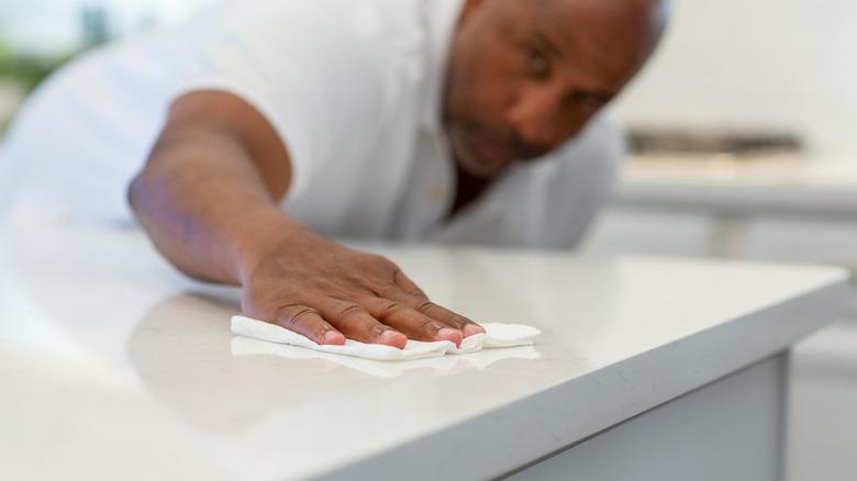 Man wiping a white countertop