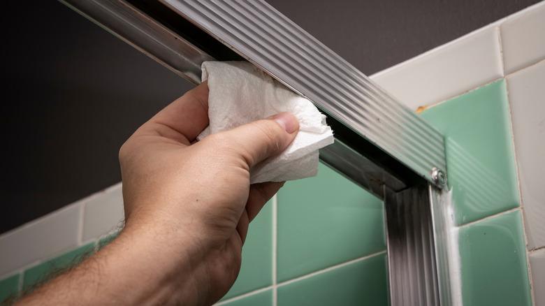Hand cleaning a shower door track