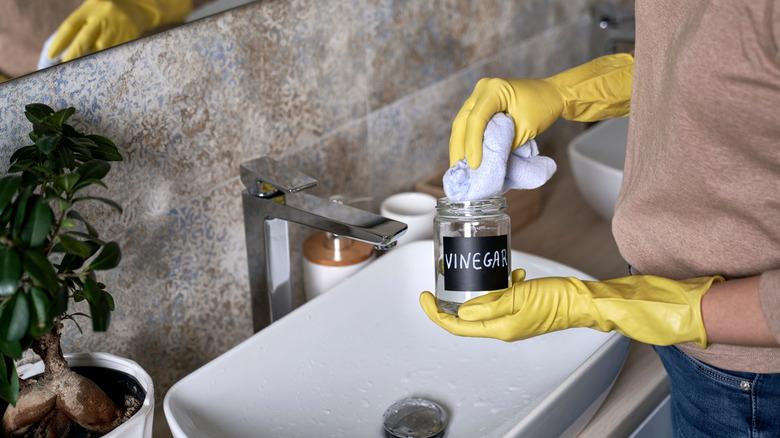Person dipping rag into jar of vinegar