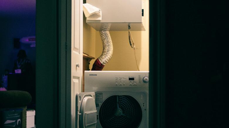 dimly lit laundry room with visible, large dryer vent piping