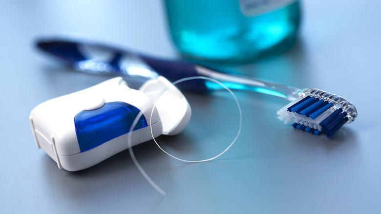 A case of dental floss sitting alongside a toothbrush and mouthwash.
