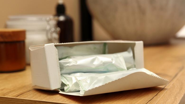 An open box of tampons sitting on a vanity in a bathroom.